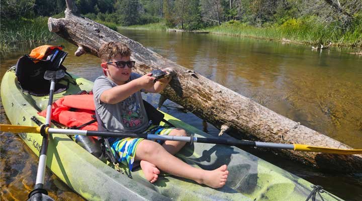 boy holding a turtle on the AuTrain River