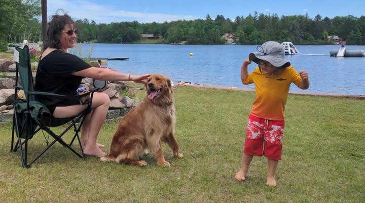 Woman with golden retriever sitting by the lake