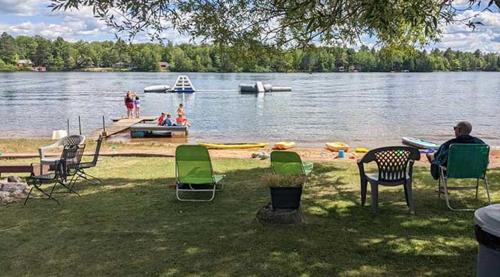 Grandparent sitting in the shade watching children play by the lake